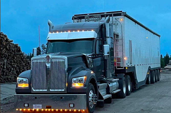 Kenworth TFB avec remorque à copeaux à la cour à bois au crépuscule