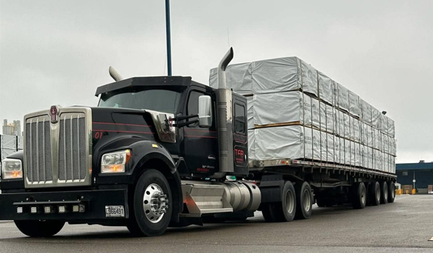 Kenworth noir TFB avec flatbed chargé de paquets de sciage emballés